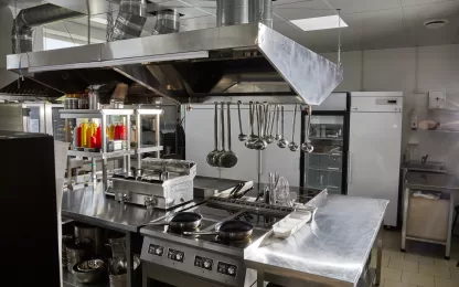 Cozinha profissional equipada com estruturas em aço inox e utensílios organizados, ambiente que demanda o uso de uma lavadora de louças industrial.