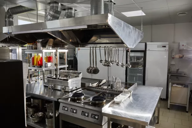 Cozinha profissional equipada com estruturas em aço inox e utensílios organizados, ambiente que demanda o uso de uma lavadora de louças industrial.
