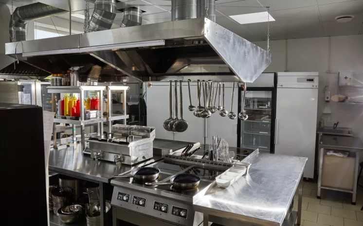 Cozinha profissional equipada com estruturas em aço inox e utensílios organizados, ambiente que demanda o uso de uma lavadora de louças industrial.