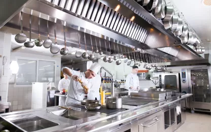 Cozinha industrial equipada com lavadora de louças industrial profissional e chefs em operação.
