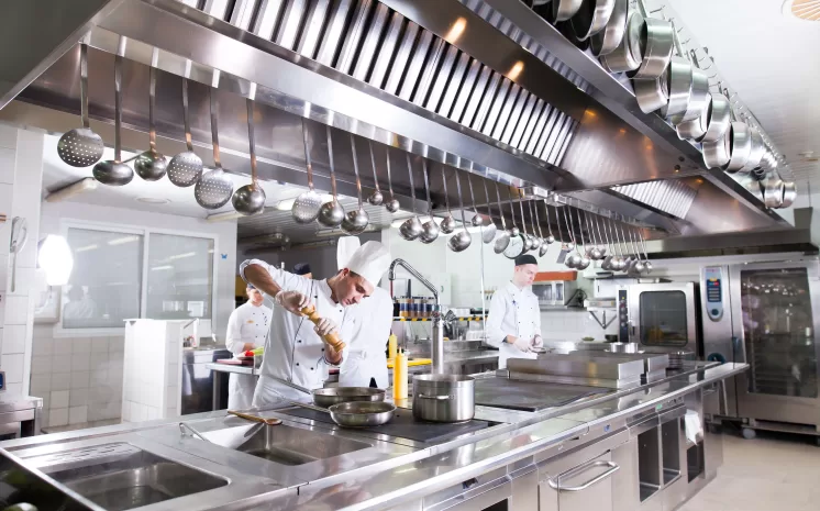 Cozinha industrial equipada com lavadora de louças industrial profissional e chefs em operação.